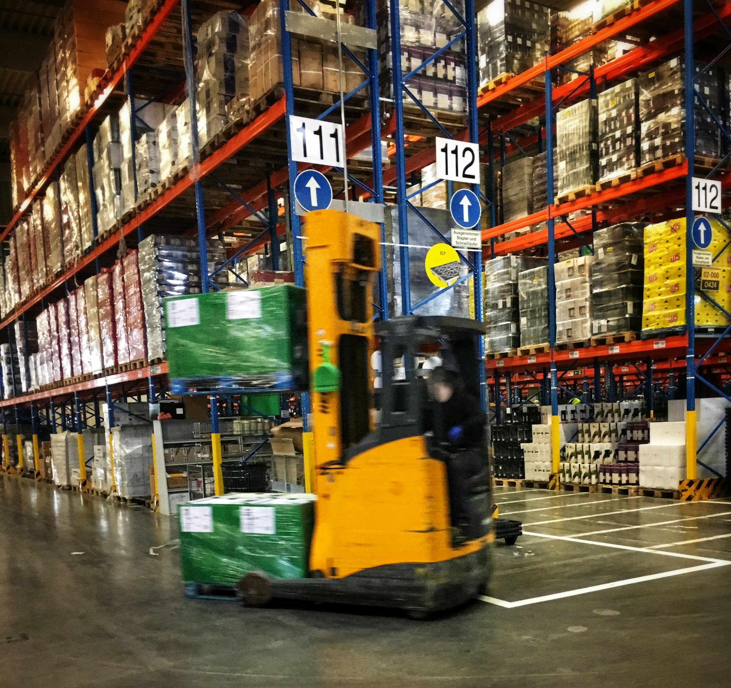 A forklift moving pallets between warehouse racks