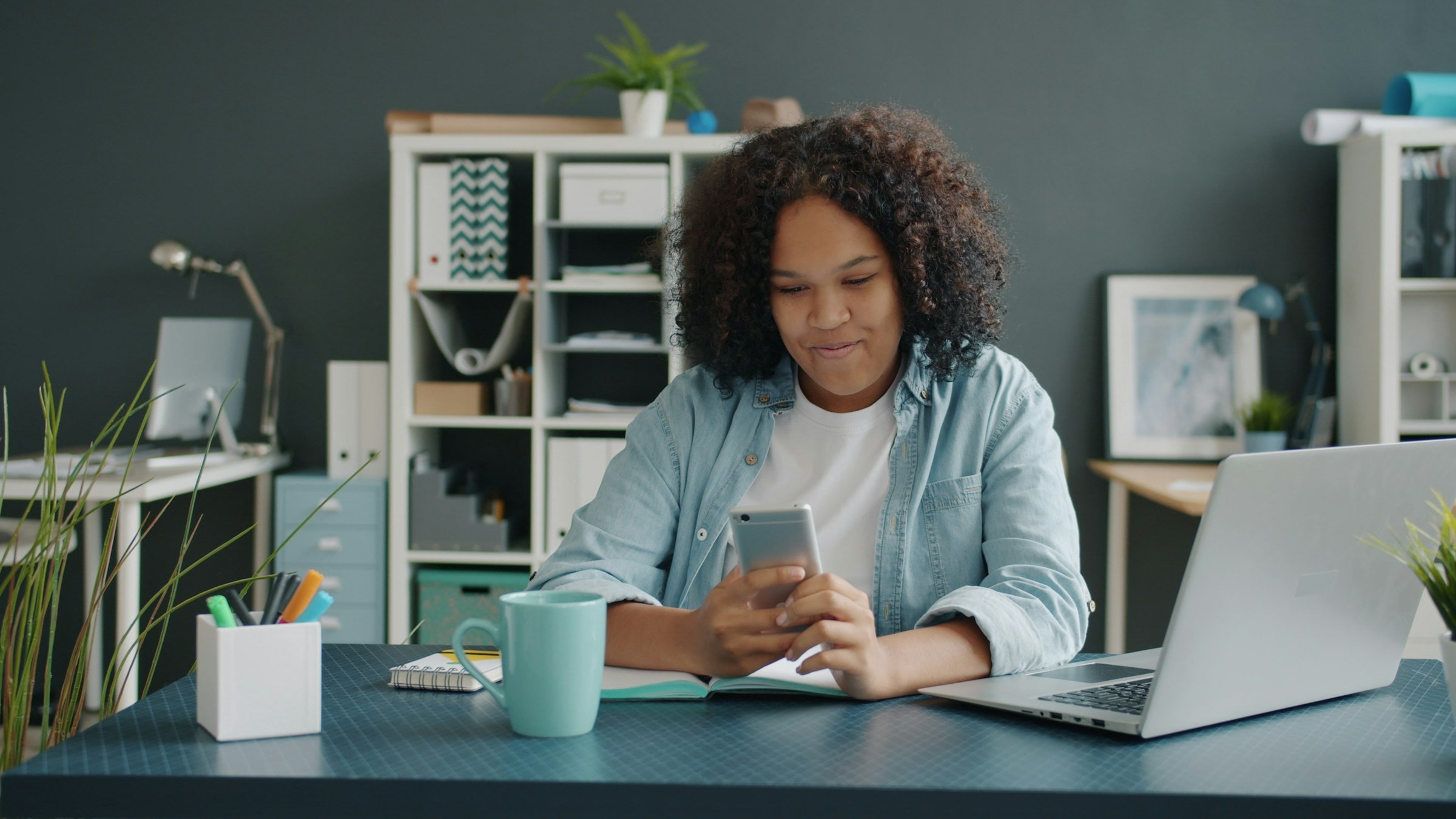 A woman replying to a message on her phone at her desk